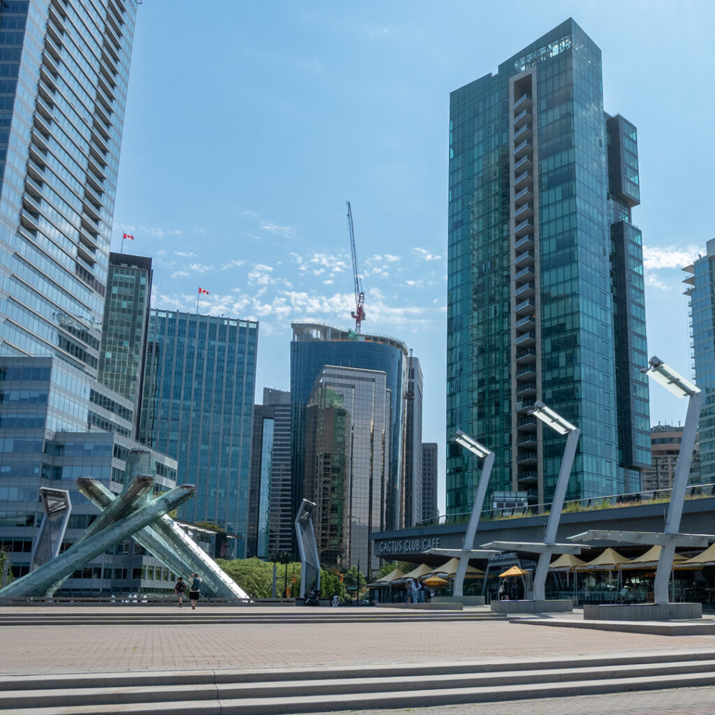 ground view of downtown vancouver buildings and olympic torch